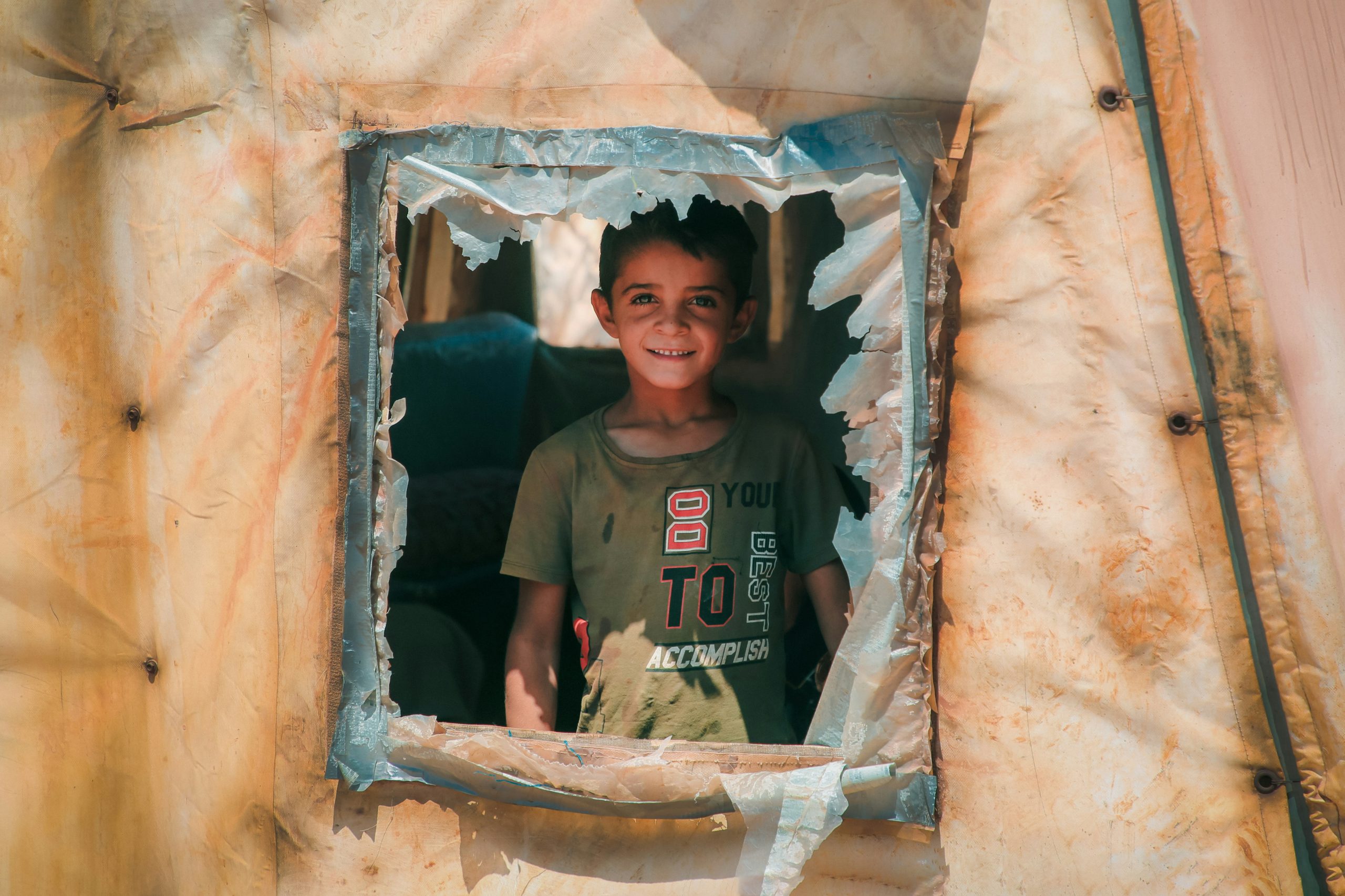 Home 4 Child smiling inside refugee camp tents