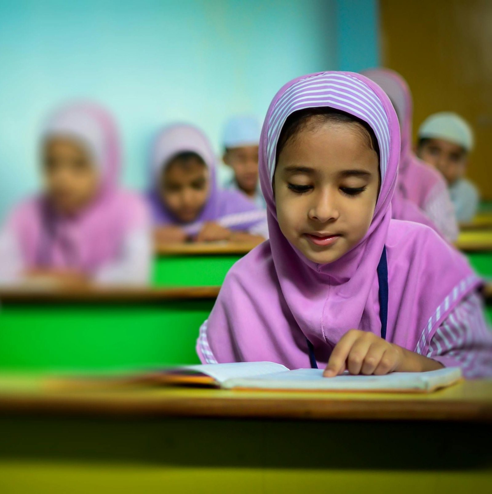 Group of young students in traditional hijabs focusing on their studies in a classroom.
